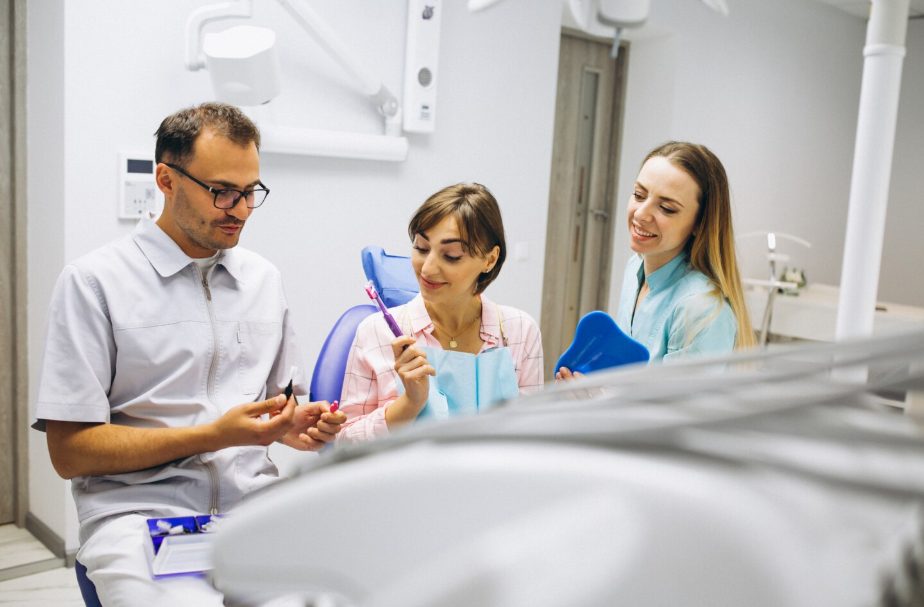 Dentist showing patient a complete dental hygiene kit with assistant in clinic for Dental Hygiene in Burlington.