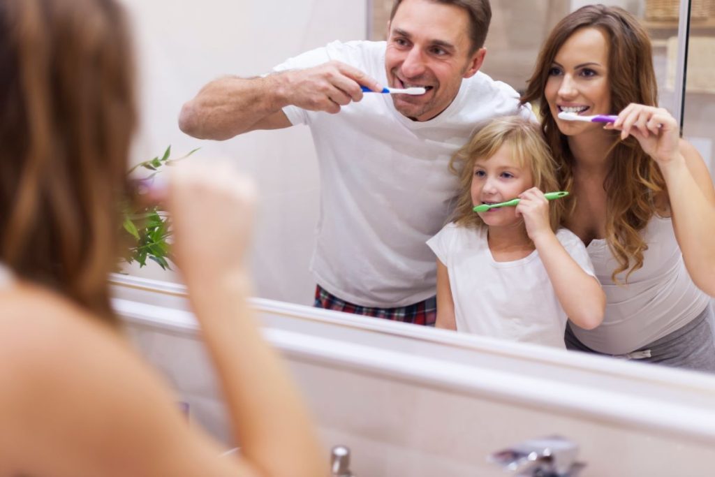 Family using toothbrushes together, promoting oral health