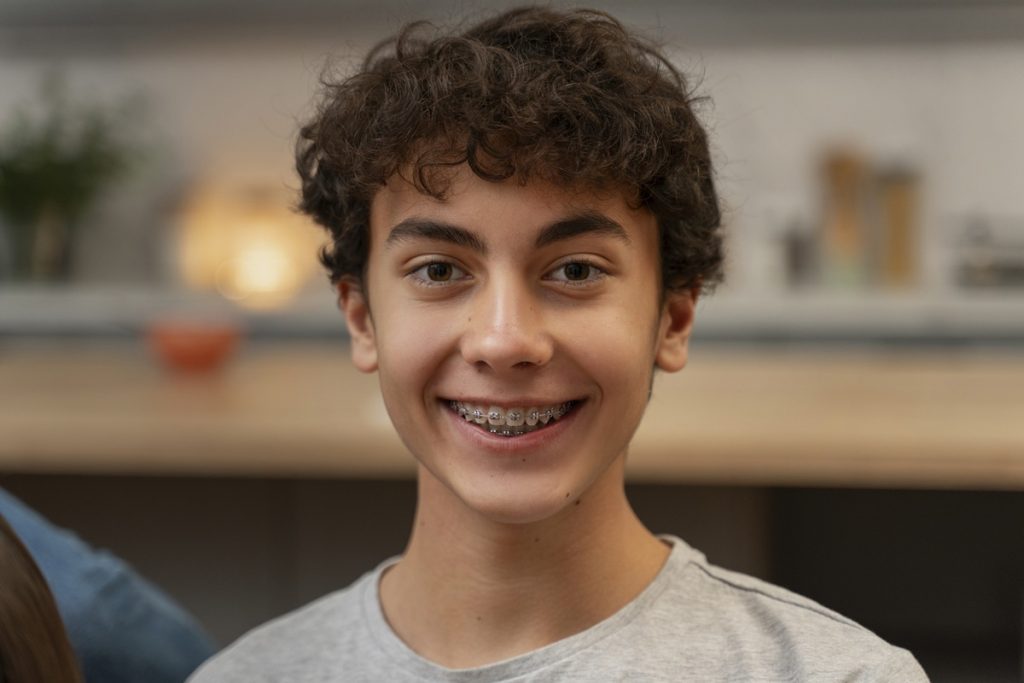 Young patient wearing traditional metal braces.