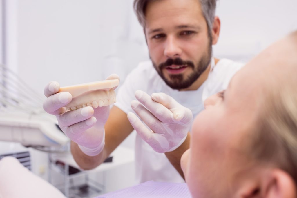 Dentist demonstrating dentures to a patient using a dental model.