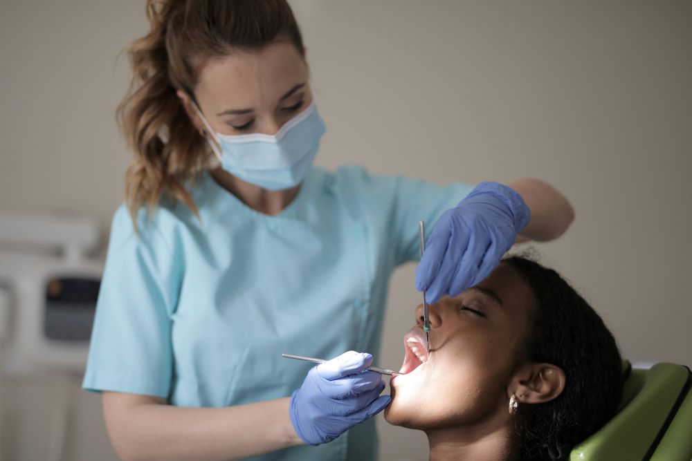 Dentist performing routine periodontal checkup on a young patient.