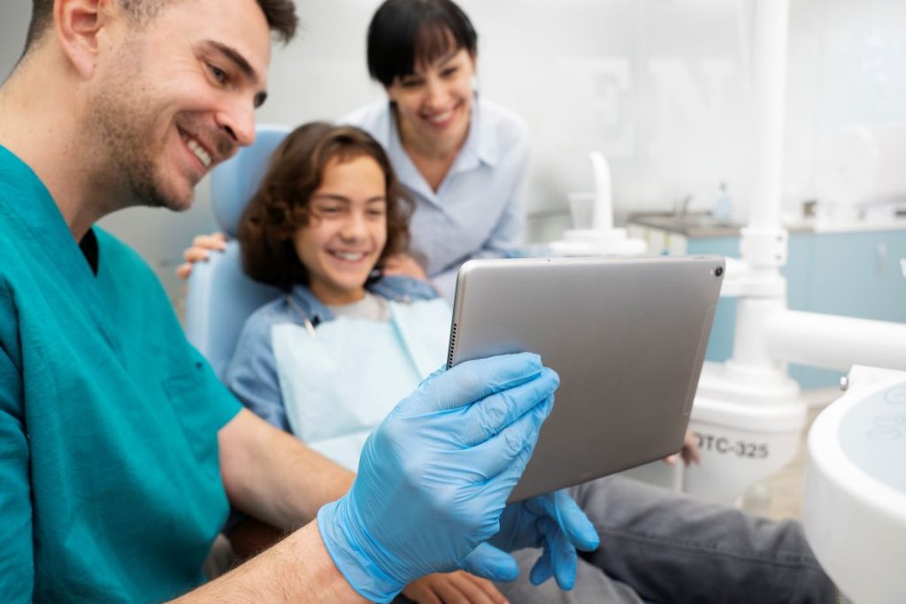 Dentist showing a young boy and his mother a dental scan on the screen during a routine check-up.