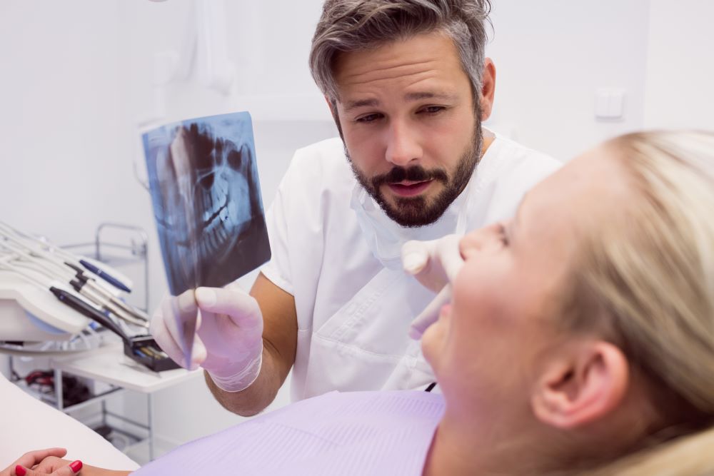 Dentist explaining wisdom tooth X-ray to patient in a calm, safe dental setting.