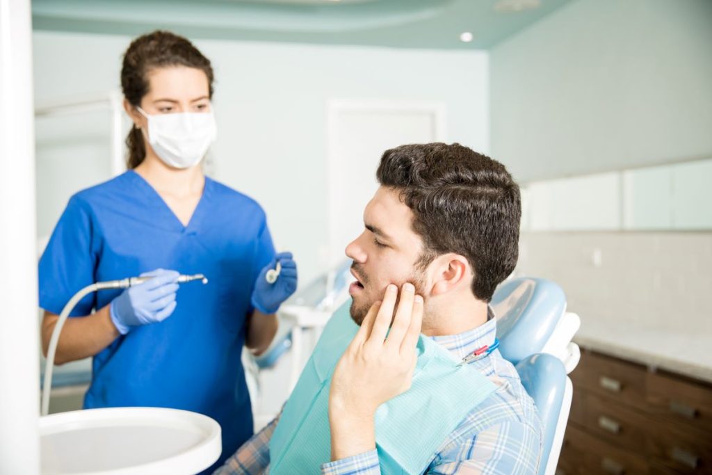 Dentist examining a patient experiencing tooth pain for possible extraction