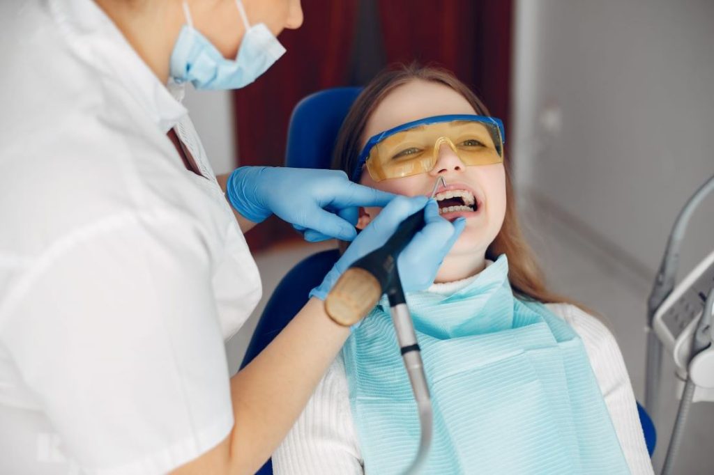 Young woman undergoing dental hygiene procedure by dentist for a healthier smile.